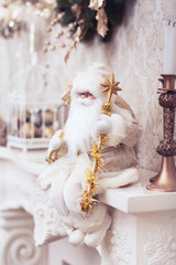 Winter Christmas decoration, Xmas white Santa sitting on classical fireplace with golden stick.