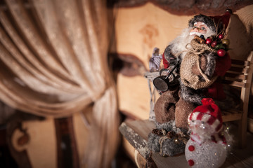 Little Christmas Santa Claus sitting on a chair at the wooden background. Xmas scene.