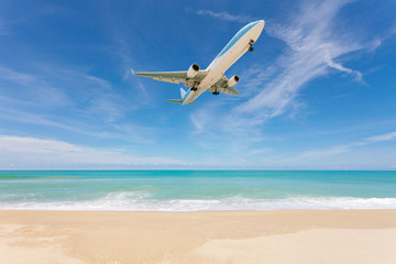 Fototapeta na wymiar Airplane landing above beautiful beach and sea background.