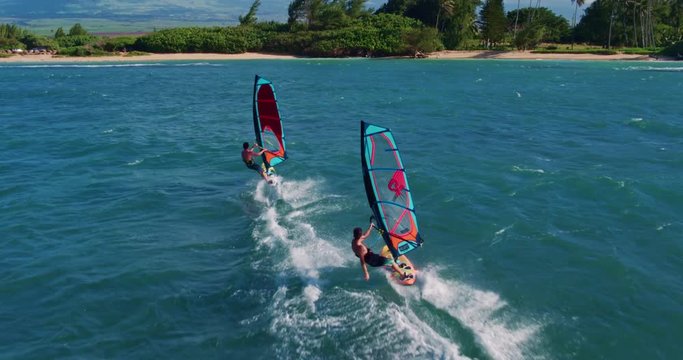 Aerial view of windsurfers gliding across blue ocean, extreme sport