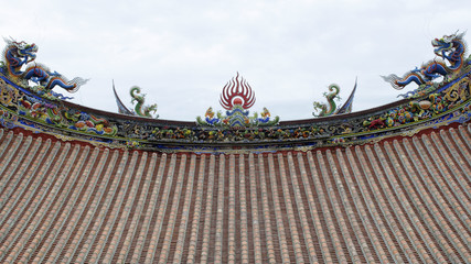 Chinese temple roofs. Two blue and two green dragons on each roof, one sun in the center, fish and other historical characters along the edge of the roof painted in red, yellow, blue, green and white.