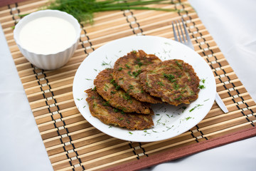 Delicious homemade potato pancakes on plate with sour cream, selective focus