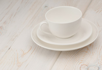 one white cup and saucer on old wooden board