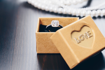 Diamond ring in the box on wooden table. Opened gift jewelry box. Box with the name of 