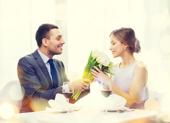 smiling man giving flower bouquet at restaurant
