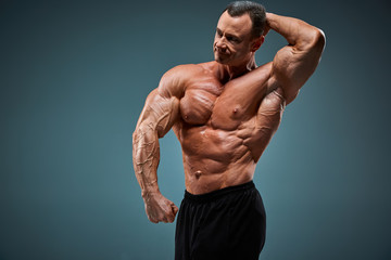 torso of attractive male body builder on gray background.
