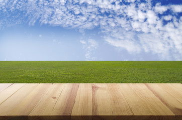 Field of green grass and sky cloudy wood table