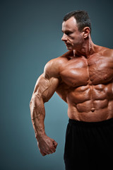 torso of attractive male body builder on gray background.