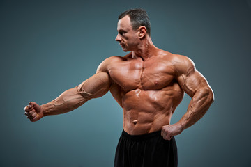 Fototapeta premium torso of attractive male body builder on gray background.
