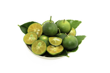 Cut limes and green leaves in a small bowl on white background.