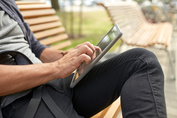 close up of man with tablet pc sitting on bench