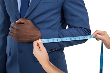Mid section of woman measuring businessman sleeve