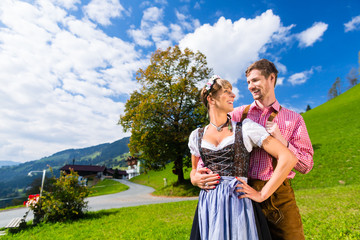 Paar in Tracht steht auf Alm in den Alpen