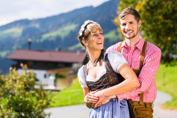 Paar in Tracht steht auf Alm in den Alpen