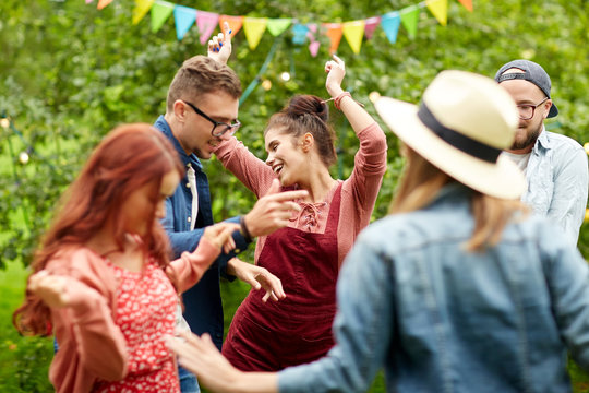 happy friends dancing at summer party in garden