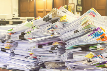 Pile of documents on desk stack up high waiting to be managed