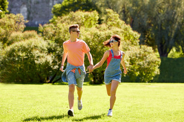 happy teenage couple running at summer park