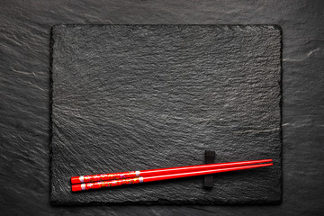 Two chopsticks on black stone background with copyspace, top view