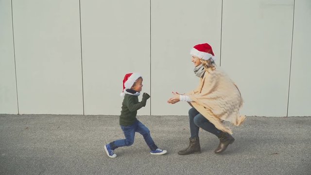 mutter und sohn mit weihnachtsm&uuml;tze laufen im freien