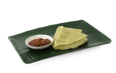 Two slices of homemade plain pancake with shrimp gravy or sambal udang on green banana leaf plate on white background