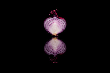 Half red onion isolated on black reflective background
