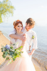 the happy couple groom and bride with wedding bouquet are on the beach