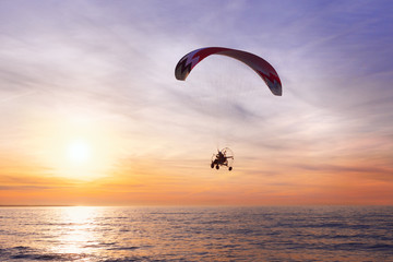 Motor Glider flying over the sea during sunset