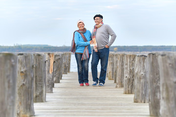 lebensfrohes Seniorenpaar beim Herbstspaziergang am See