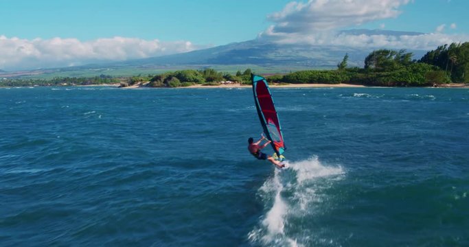Aerial view of windsurfer gliding across blue ocean, extreme sport