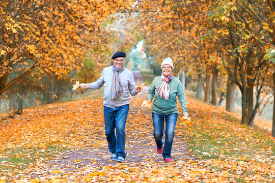 hüpfendes lachendes Paar im Herbst, Senioren