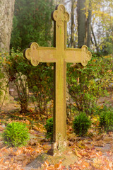Old, iron cross with symbols in the cemetery in sunny autumn day. Peaceful place. Cemetery in Europe, Latvia.
