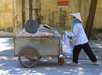 woman in mask is transporting a cart with clothes - 125017885