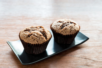 Chocolate muffins on black plate withwooden floor