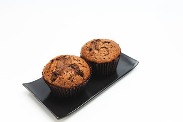 Isolated chocolate muffins on black plate with white background,