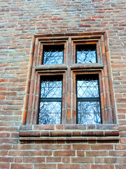 Riflessi del cielo sul vetro della finestra incorniciata da mattoni rossi Torino Italia