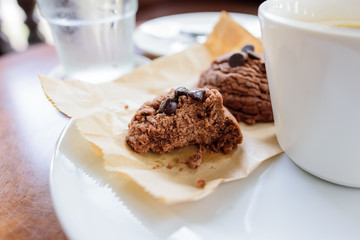 Black coffee cup with chocolate cookie on wooden background