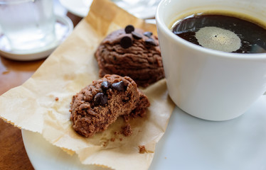 Black coffee cup with chocolate cookie on wooden background