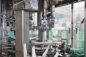 Industrial factory indoors and machinery. Robotic factory line for processing and bottling of pure spring water into canisters and bottles. Selective focus. Short depth of field.