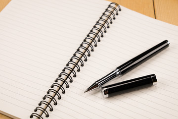 pen and book on wood background