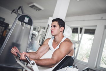 Fototapeta premium Young attractive adult man exercising and doing weight lifting at fitness gym. Sport training indoors.