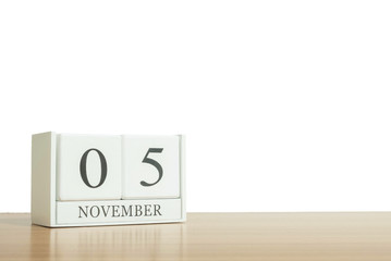 Obraz premium Closeup surface white wooden calendar with black 5 november word on blurred brown wood desk isolated on white background with copy space , selective focus at the calendar
