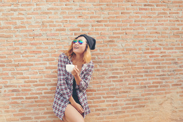 Cheerful woman in the street drinking morning coffee against bri