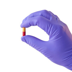 Male hand in medical glove with pill isolated on white.