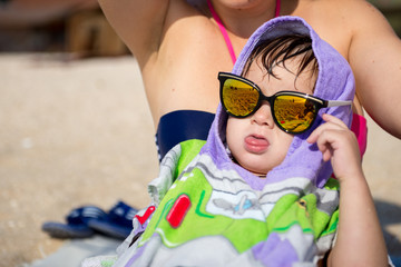 Happy young mother and son on a tropical beach with the laughing little boy.