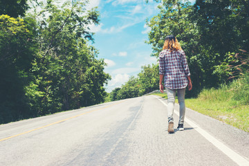 Young hipster woman walking away on side road alone.