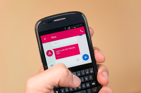 Friendzone - modern love rejection through mobile phone. Caucasian hand writes / reads text message of being friendzoned by potential love partner