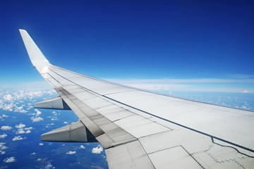 Fototapeta na wymiar Airliner wing in flight on blue sky background