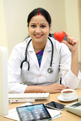 Young female doctor holding red heart shape