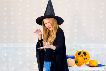 Teenager girl in witch costume posing with pumpkins