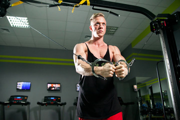 Athletic strong bodybuilder deals with a dumbbell in the gym